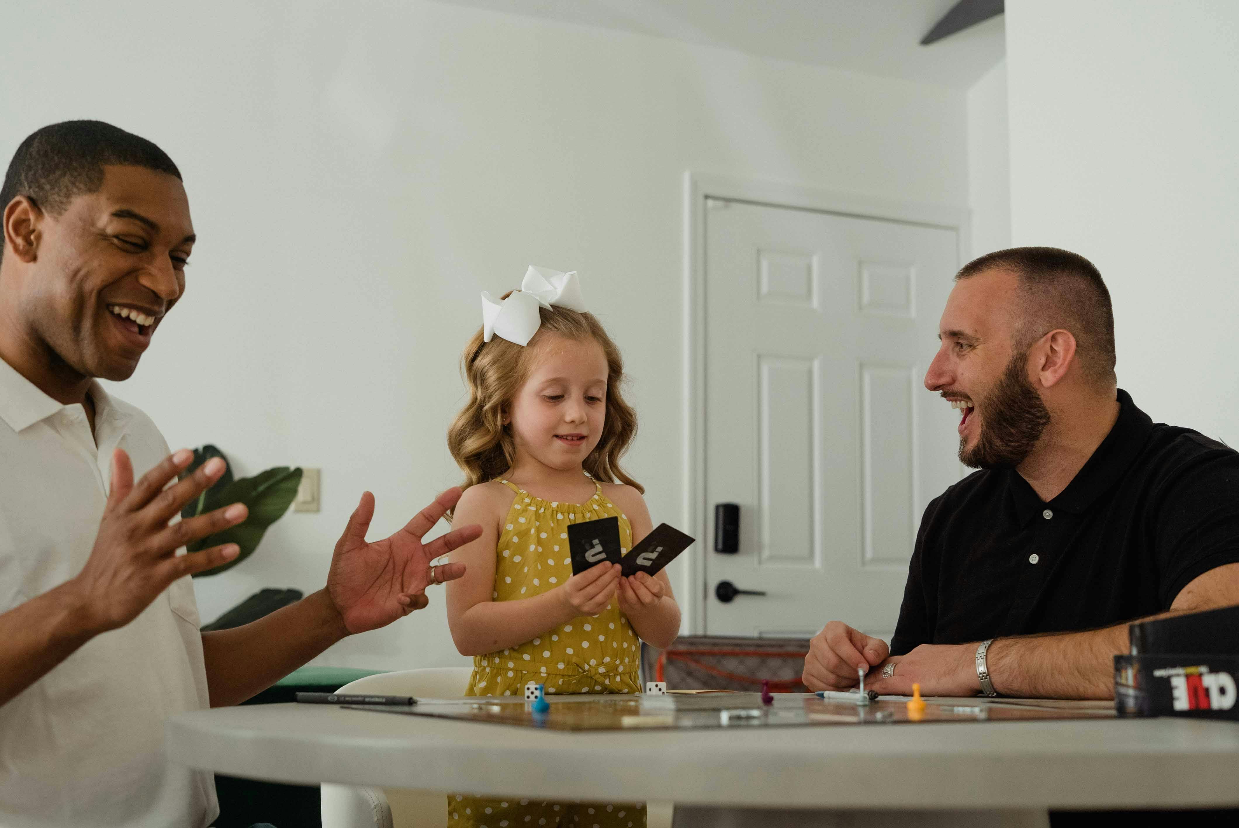 A family of four playing a colourful strategy board game together at a kitchen table